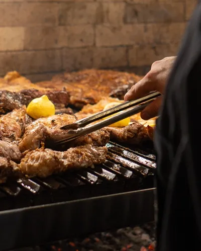 Tongs turning a cut of meat on the grill
