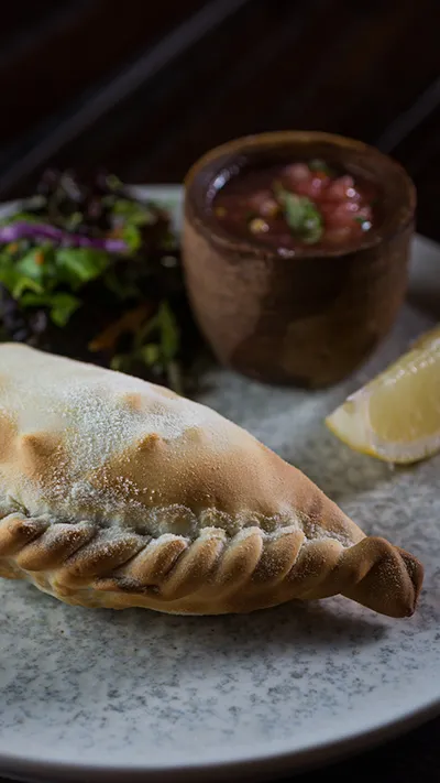 Empanada argentina com repulgue feito à mão e molho criollo