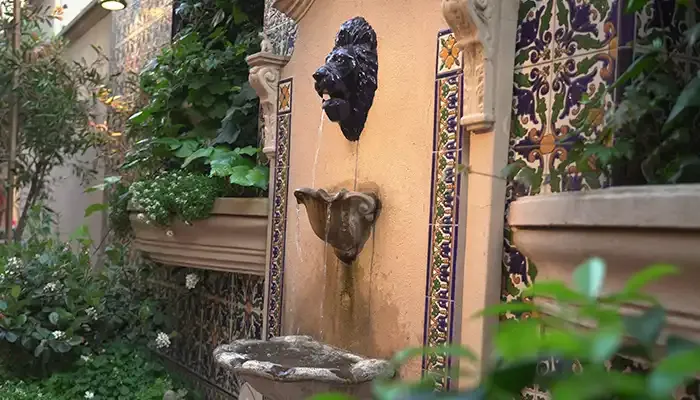 Fonte de pedra com azulejos entre a vegetação do pátio