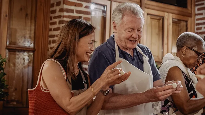 Invitados con delantal riéndose mientras arman empanadas