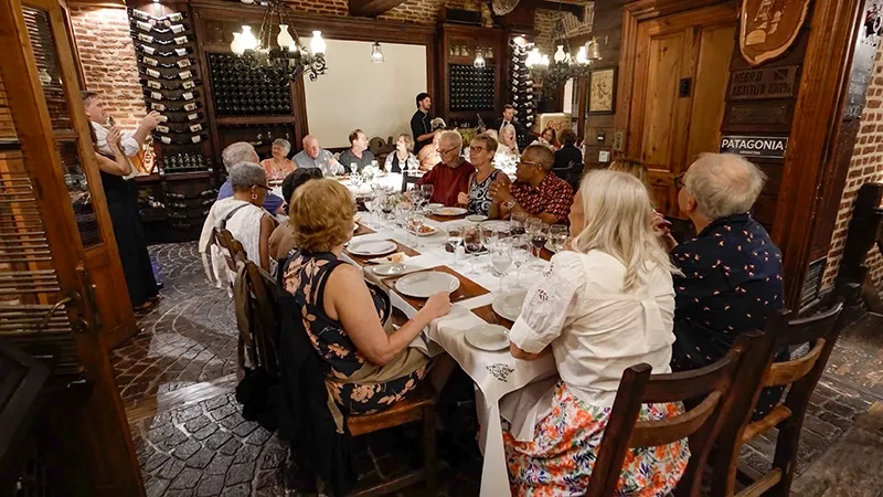 Cena en el salón de la cava, con la mesa larga rodeada de botellas de vino
