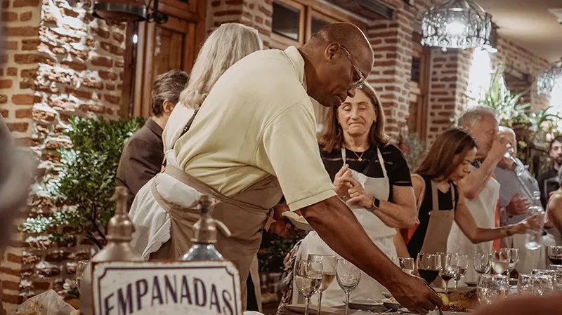 Invitado con delantal armando empanadas junto a la mesa, con el cartel de empanadas