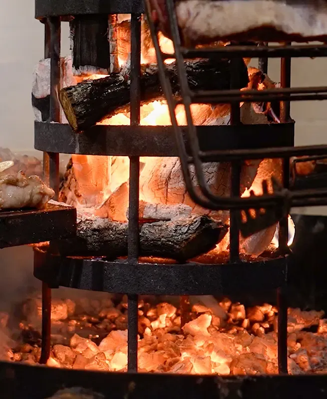 Fuego de leña en un brasero de hierro sobre las brasas de la parrilla de RoofTop San Telmo